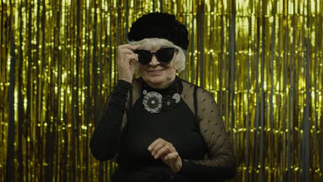 elderly stylish grandmother. caucasian woman posing on golden background