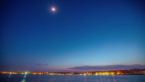 Moon-sets-over-the-town-of-Birzebbuga,-Malta-and-the-harbor---time-lapse