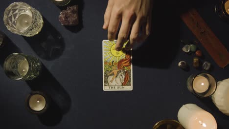 overhead shot of person giving tarot card reading laying down the sun card on table