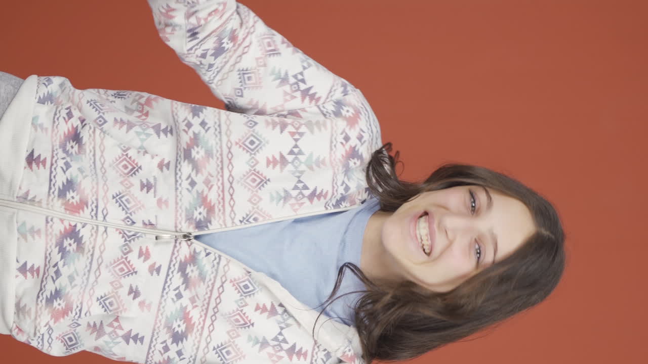 video vertical de una joven feliz saludando a la cámara.