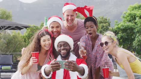 grupo feliz de amigos diversos tomando selfies en la fiesta de navidad en el jardín