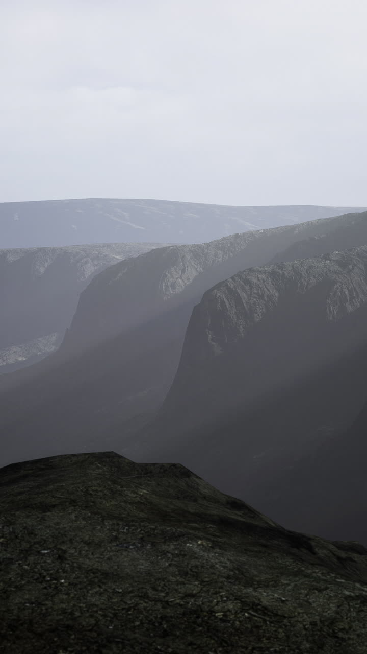 Misty mountain ranges reveal majestic cliffs under a cloudy sky