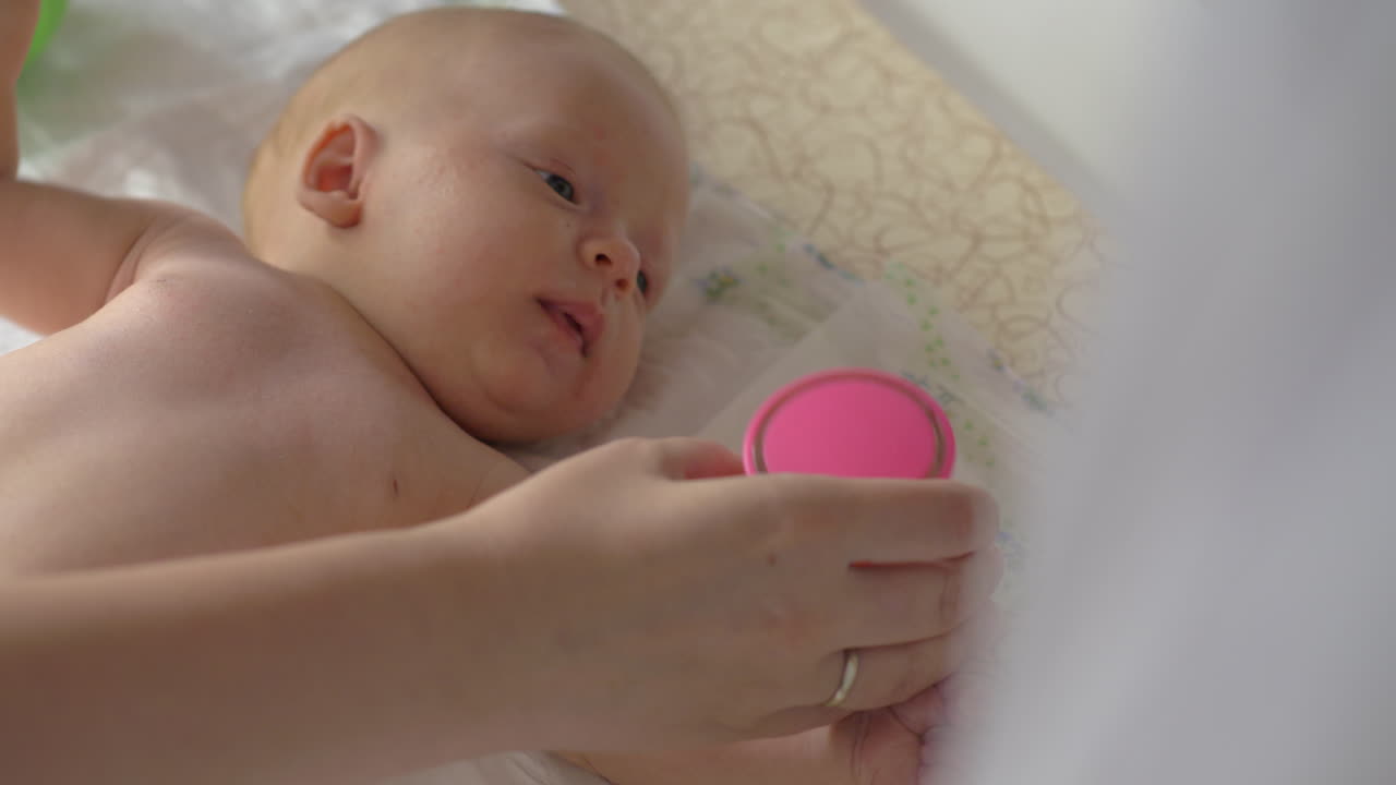 Baby girl of two month lying in crib with rattle box