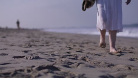 Middle-aged-white-woman-walking-barefoot-on-Venice-Beach-in-California-in-slow-motion