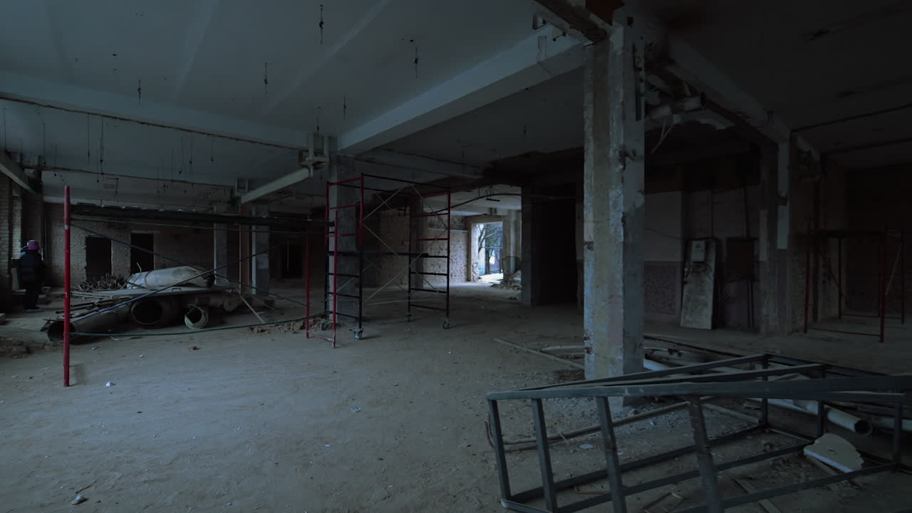 Large spacious room with columns. Some debris and scaffolding are scattered by the premise.