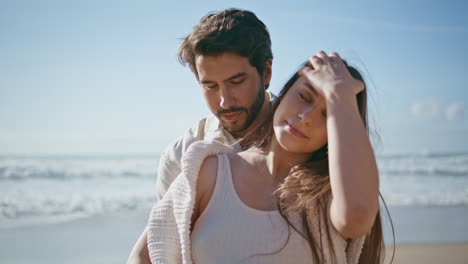 affectionate pregnant couple posing on sunny beach close up. spouses relaxing