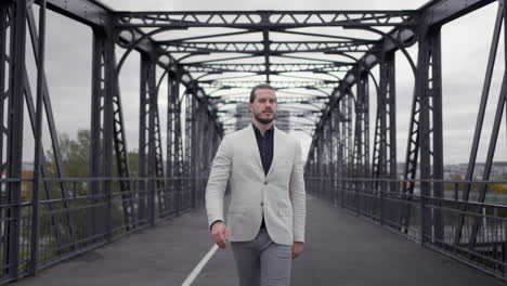 confident adult businessman in formal suit walking through the bridge at the morning