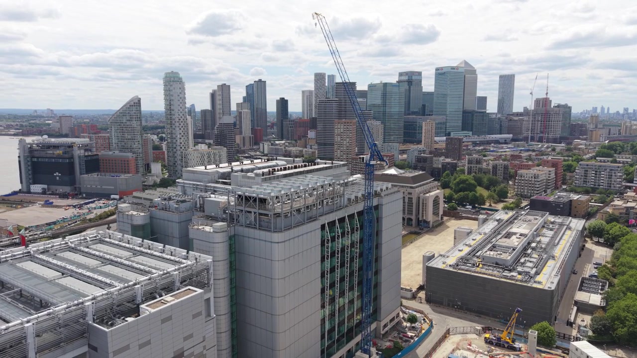 Stedelijke ontwikkeling in London Canary Wharf omvat nieuwe datacentrumgebouwen. Kranen zijn actief boven de locatie, tegen de achtergrond van de skyline en de Theems onder een heldere, bewolkte hemel