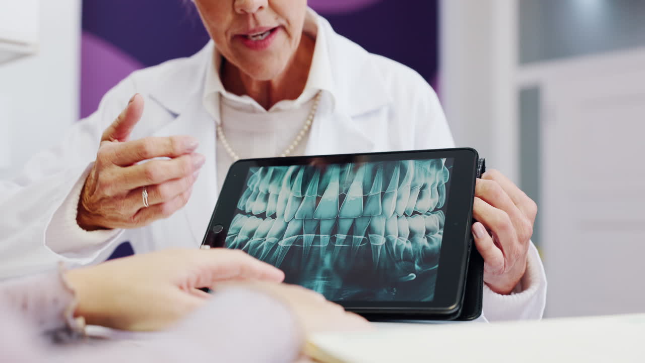 Dentist explaining dental x-ray on tablet to patient