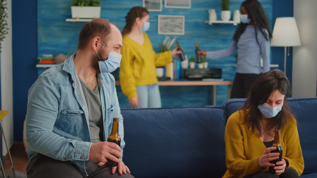 Friends with protection mask socializing during party sitting on sofa
