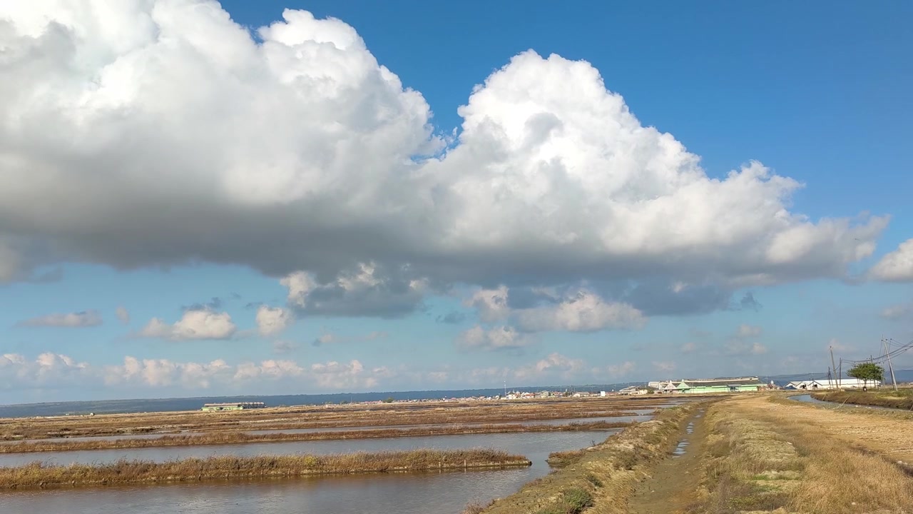 Salt Pans and Large White Clouds Under a Blue Sky