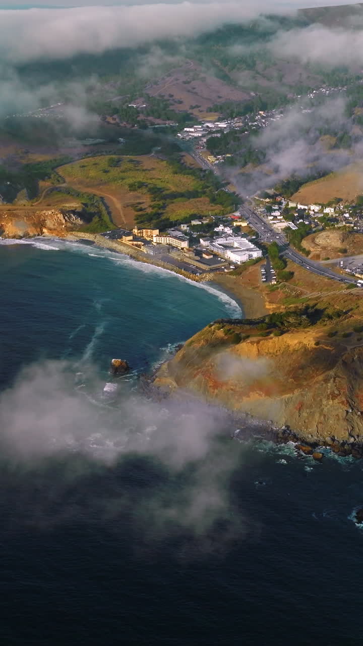 Beautiful rocky coast of sunny Montara State Beach from water. Fog moving on the land from the ocean. Top view. Vertical video