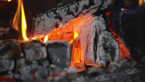 close up view of fire or campfire of aspen logs burning focusing on the coals, with yellow flames, stationary shot with no movement