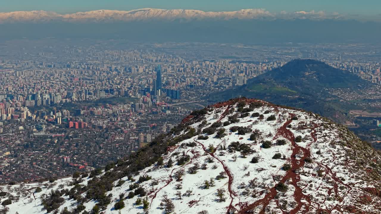 Aerial Drone fly Santiago de Chile city, Snowy Manquehuito Hill Summit in Winter, Andean Cordillera Mountain Town, Panoramic