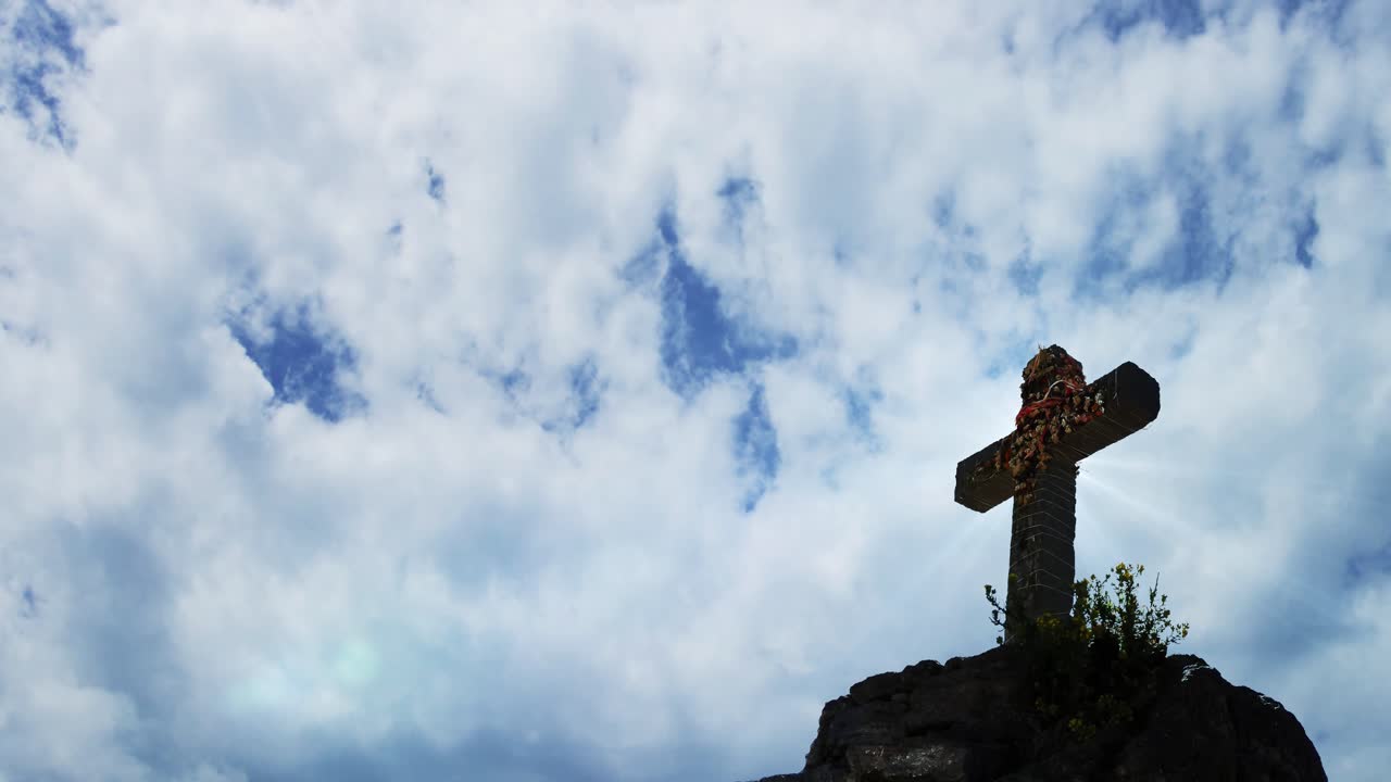 하늘에 구름의 저속 배경으로 산 위에 십자가의 동상