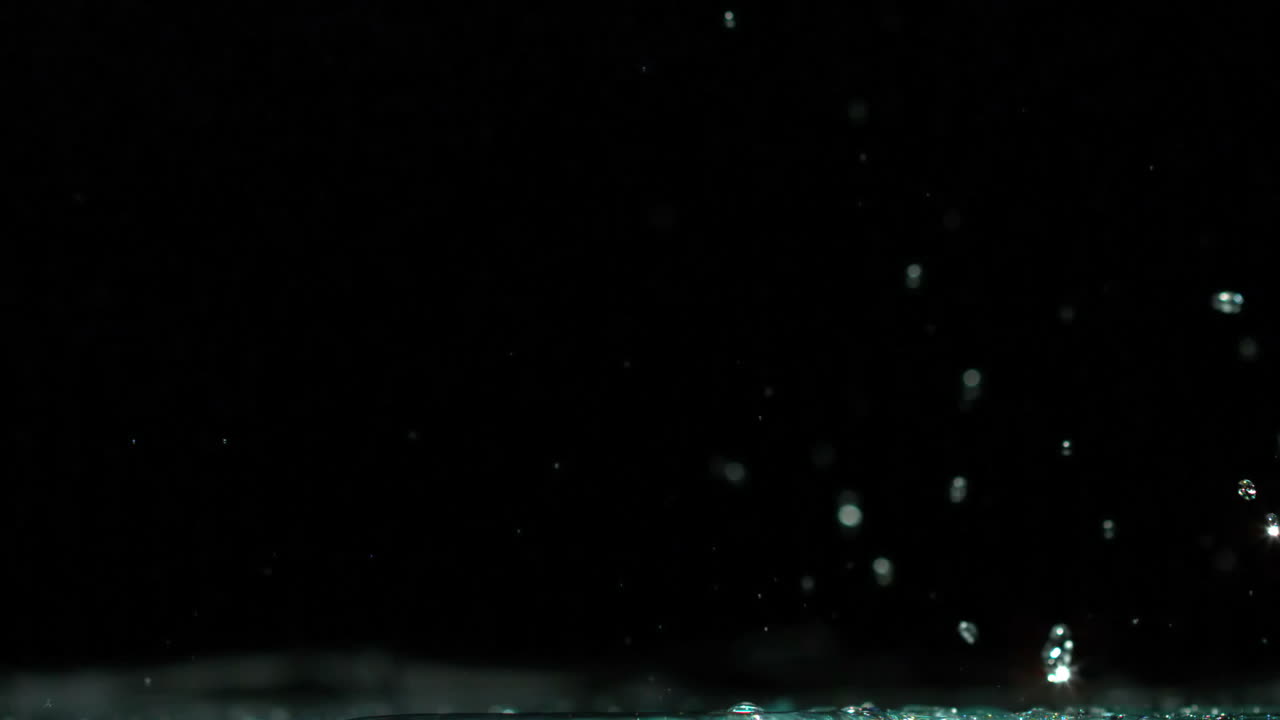 Toy car rolling over puddle and splashing on black background