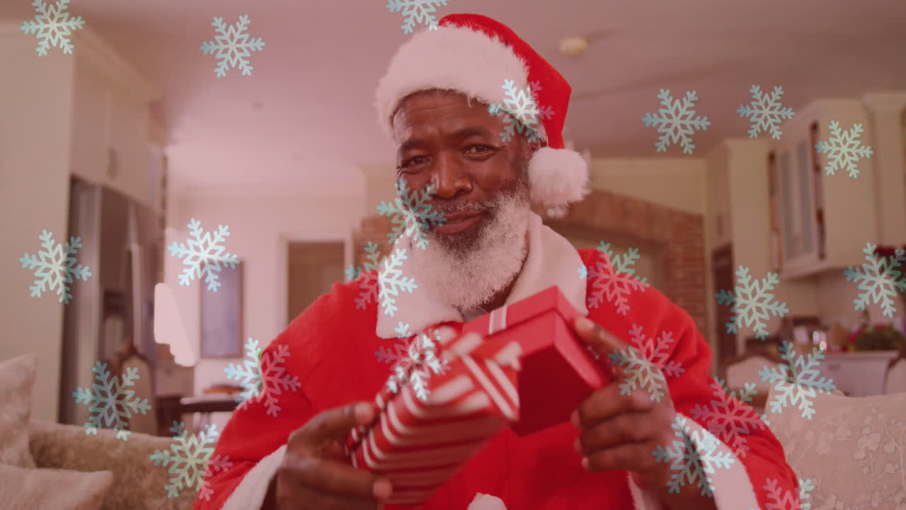 animación de nieve cayendo sobre un hombre sonriente vestido con disfraz de papá noel y haciendo una videollamada