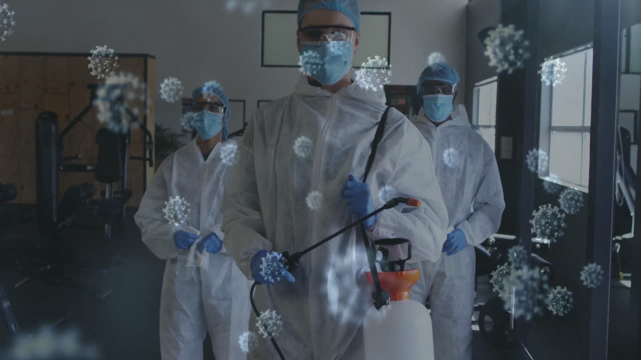 múltiples células de covid-19 flotando contra el retrato de un equipo de trabajadores de la salud de pie en el gimnasio