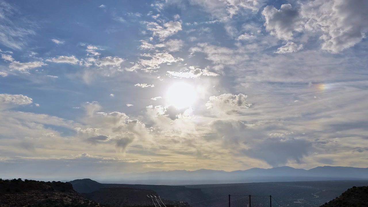 Un timelapse con drone che cattura nuvole ipnotiche che si muovono sopra un paesaggio desertico del sud-ovest a tarda mattinata. Le ombre si spostano dinamicamente attraverso le aspre mesas e il terreno arido.