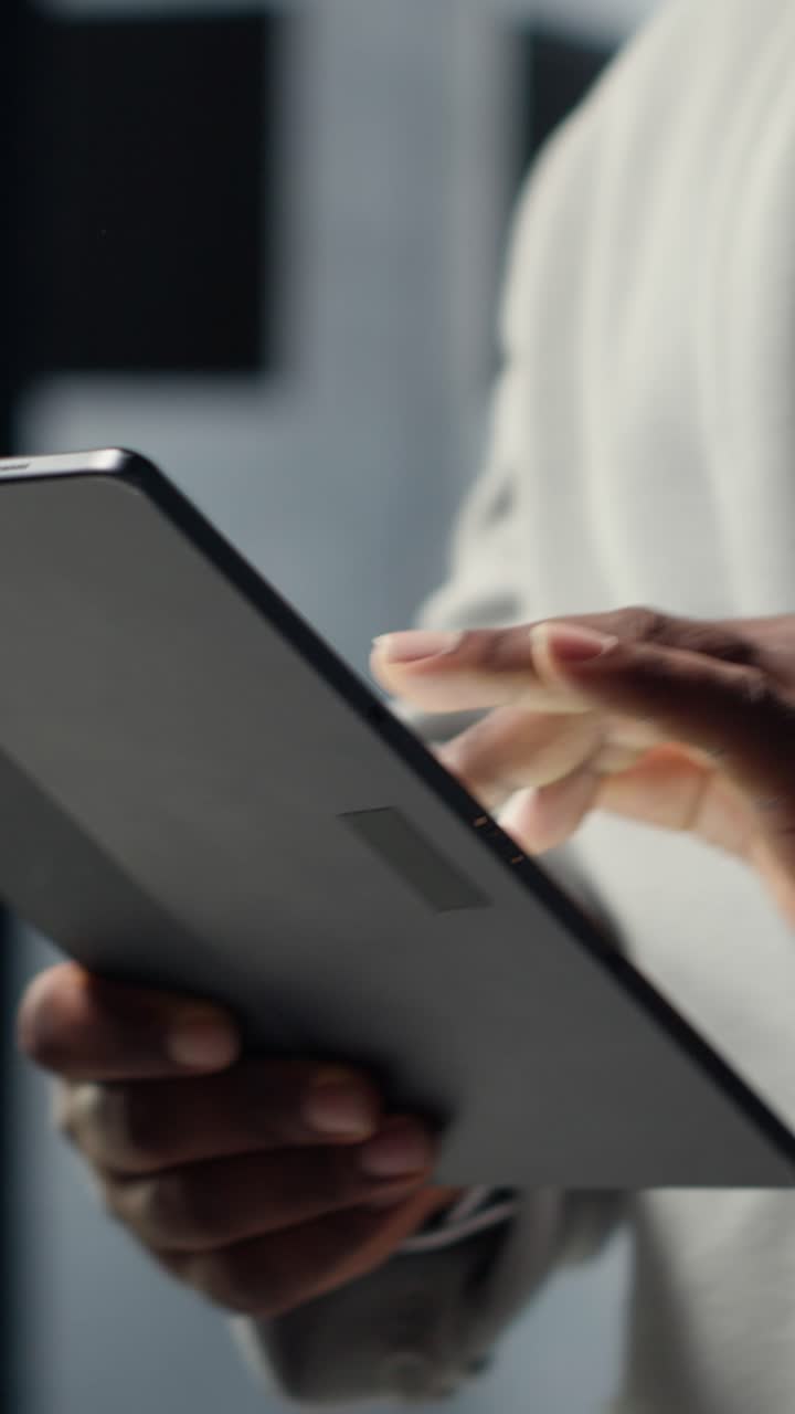 Vertical video Close up of system administrator walking in data center, using tablet