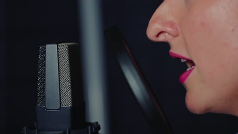 mujer cantando en un micrófono en un estudio de grabación
