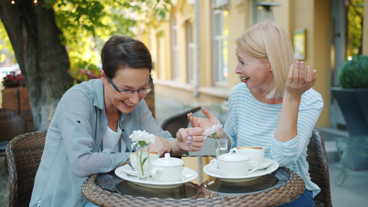 두 명의 여성이 야외 카페에서 커피를 즐기고 있습니다.