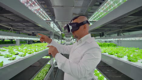 un microbiólogo masculino moderno usa gafas de realidad virtual para controlar y administrar el clima en una moderna granja de verduras orgánicas.