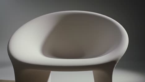 sleek and modern chair design showcased in two frames, highlighting unique curvature and aesthetic appeal in a minimalist setting
