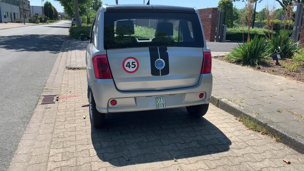 Rear view of a silver microcar parked on a sidewalk