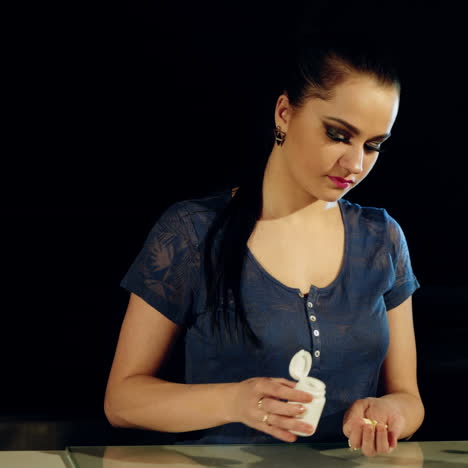 woman pours out white pills from a bottle. close up.
