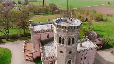 historic vecauce palace with towers and pink facade stands in latvian landscape