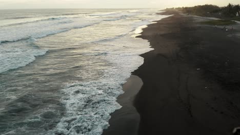 waves washing over black sand beach of el paredon in guatemala