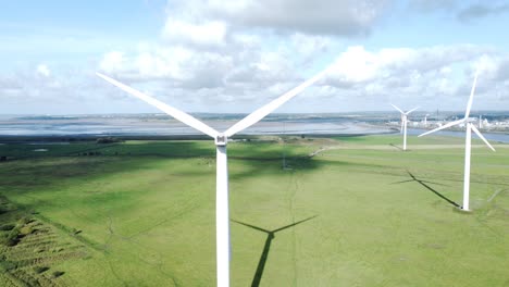 Turbinas-Eólicas-De-Energía-Verde-Alternativa-Girando-En-Los-Campos-Soleados-De-Frodsham-Cheshire-Vista-Aérea-Que-Sube-A-La-Izquierda