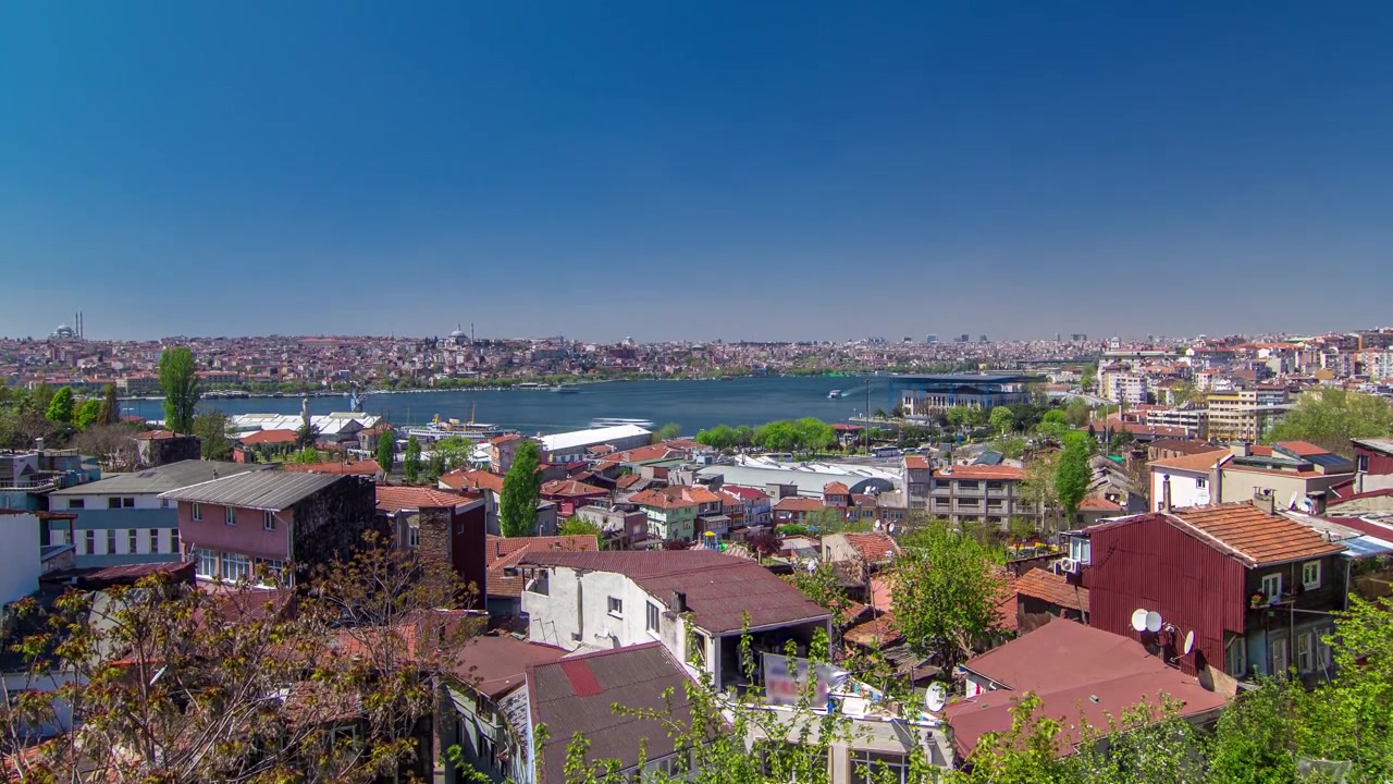 Vista panoramica dall'alto con tetti rossi di case e moschee dietro il Corno d'Oro in timelapse a Istanbul, Turchia. Traghetti navigano su e giù per il Corno d'Oro.