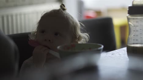 Toddler-sitting-at-the-dining-table-while-trying-to-eat-from-the-spoon