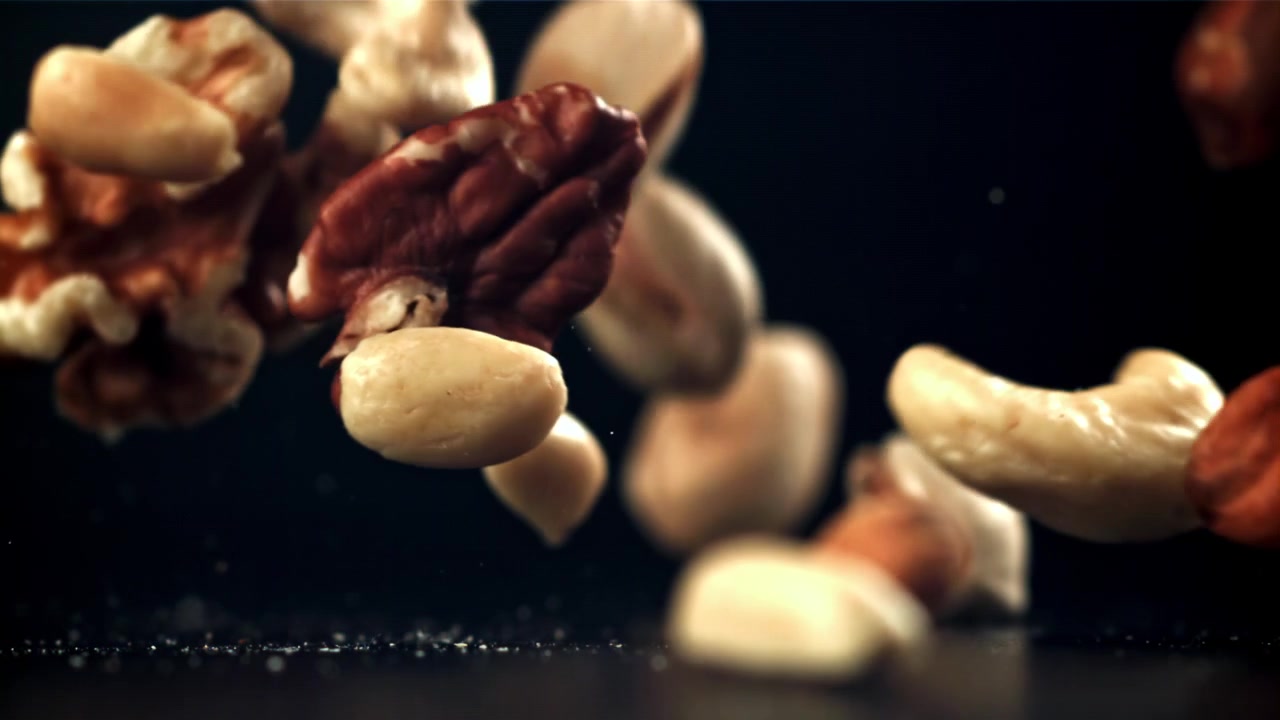 Frutta secca mista che cade al rallentatore su sfondo scuro