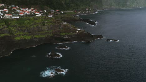 aerial view of the rocky coastline and volcanic lava formations meeting the deep blue waters of the atlantic ocean in seixal, madeira island, portugal. circle dolly