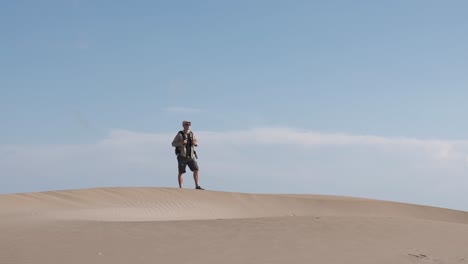 backpacker in the desert walking over a dune