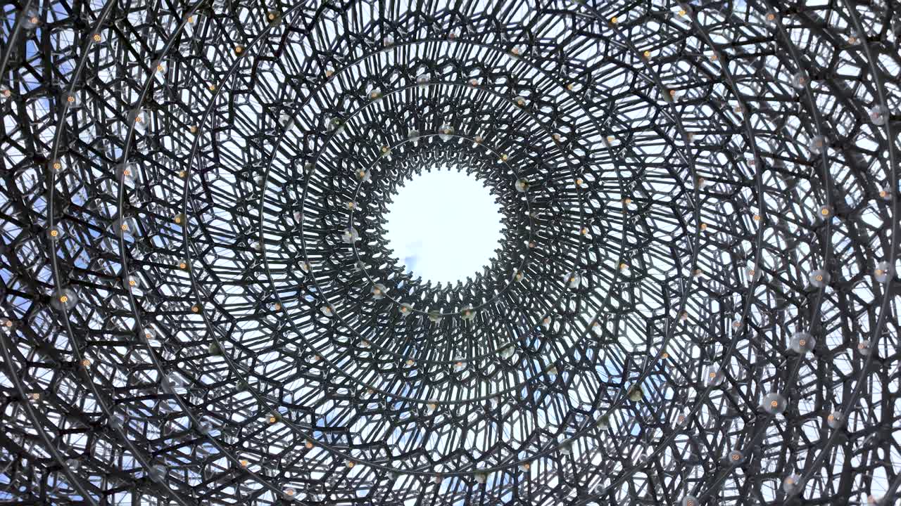 Abstract view of a circular metal structure leading towards a white-centered opening