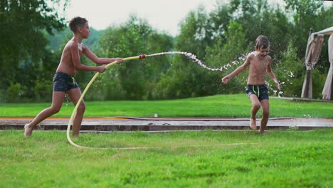 Kinder-Spielen-Im-Sommer-Mit-Wasser,-Das-Aus-Einem-Schlauch-Fließt