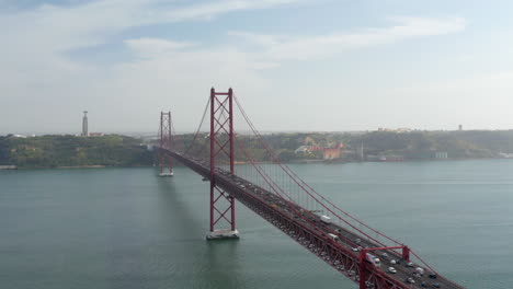 Vista-Elevada-Del-Largo-Puente-Atirantado-Rojo-Sobre-El-Río-Tajo.-Carretera-De-Varios-Carriles-Con-Mucho-Tráfico-De-Drones.-Lisboa,-Capital-De-Portugal.