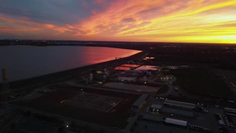 aerial forward shot of industrial city and lake hefner during colorful golden hour at oklahoma city, usa