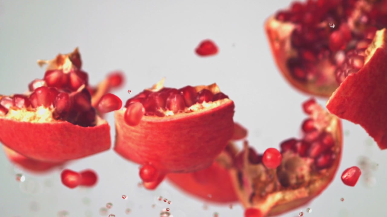 Slowmotion af friske granatæblestykker og -kerner med vandsprøjt