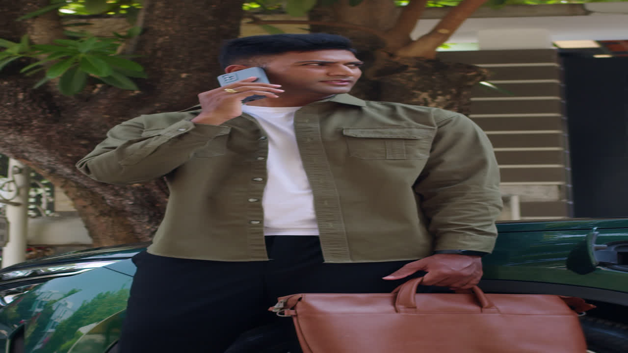 Vertical of Entrepreneur Calling on Phone Waiting for EV to Charge with Cable