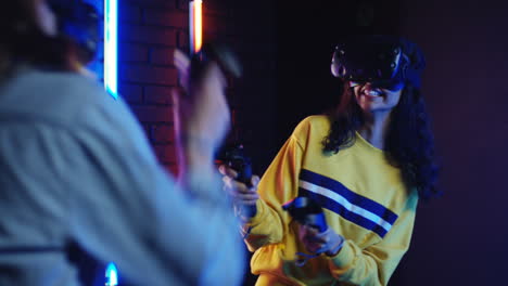 close up view of young man and woman in vr glasses and playing a virtual game in a room with colorful neon lamps on the wall