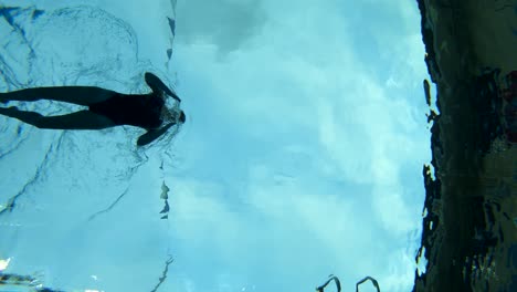 slow motion underwater shot of a woman swimming through the lane in a swimming pool using the breast stroke