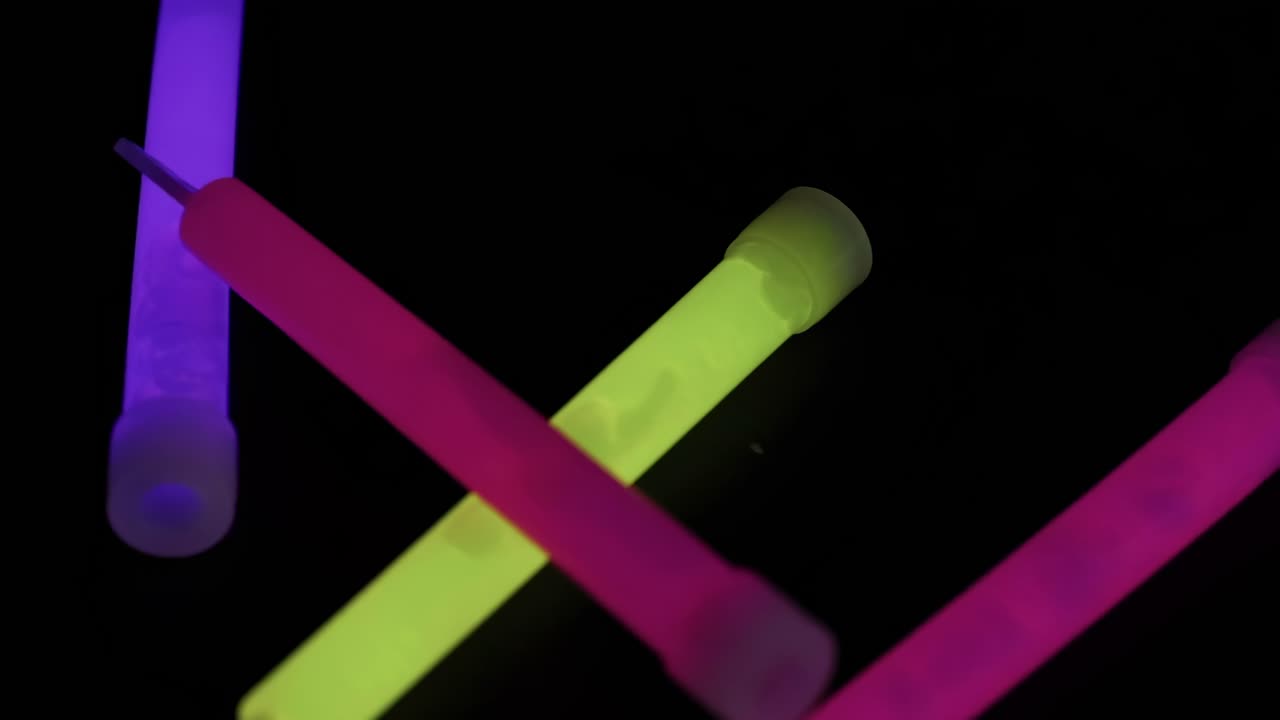 Colorful glow sticks in pink, green, and blue hues against a black backdrop.