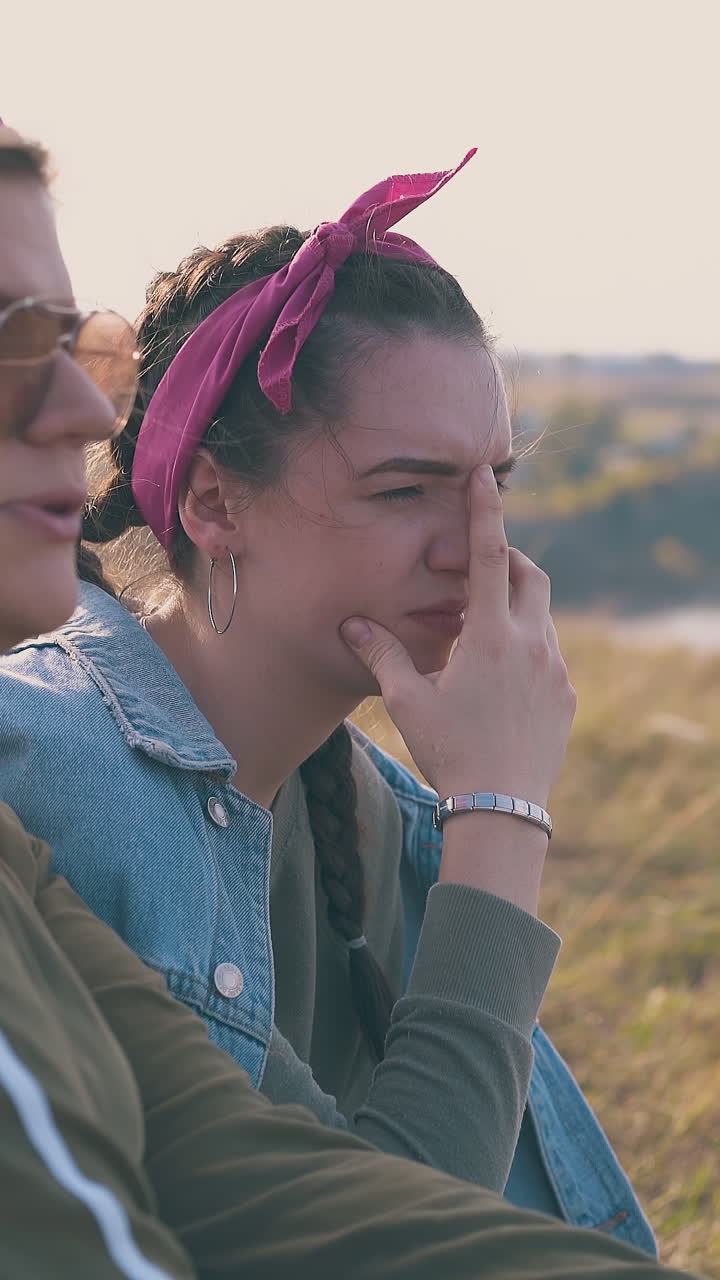 happy young women hikers talk spending time on steep river bank with grass in warm autumn evening close view