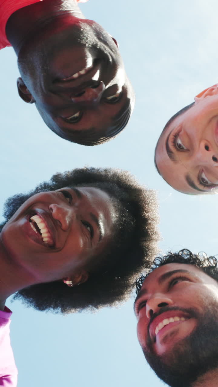 Grupo diverso e feliz de jovens adultos olhando para baixo contra o céu azul