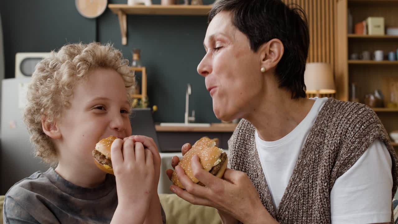 Una donna e un bambino che mangiano hamburger insieme